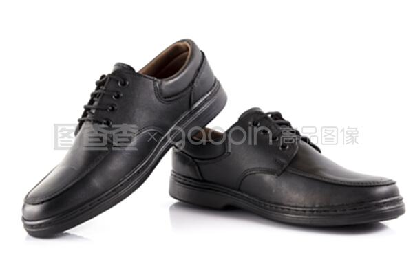 一双白色背景的黑色皮鞋,独立产品。